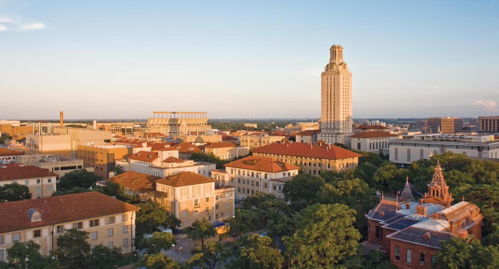 Aerial view of a major Texas university campus with its landmark clock tower at sunset